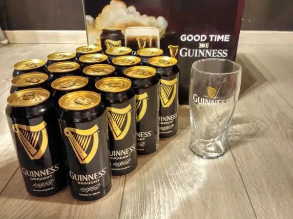 Dużo puszek piwa Guinness i szklanka, gotowe na dobrą zabawę.