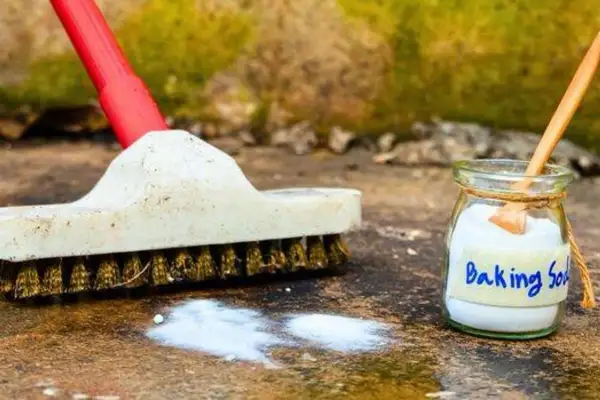 Brosse et bicarbonate de soude prêts pour nettoyer une terrasse en pierre.