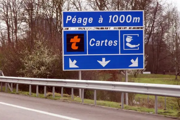 Panneau "Péage à 1000m" avec logo orange "t" et icône de carte. Indique dans quel sens mettre le badge télépéage Vinci.