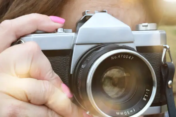 Dłoń z różowym lakierem trzyma aparat, gotowa do uchwycenia tego, czego nie można fotografować w Polsce.