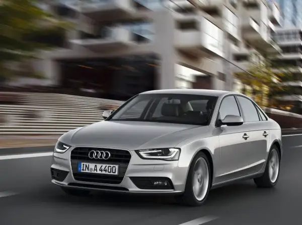 Srebrne Audi A4 B8 w ruchu miejskim. Typowe usterki tego modelu mogą dotyczyć elektroniki lub układu napędowego, ale ten egzemplarz wygląda bez zarzutu.