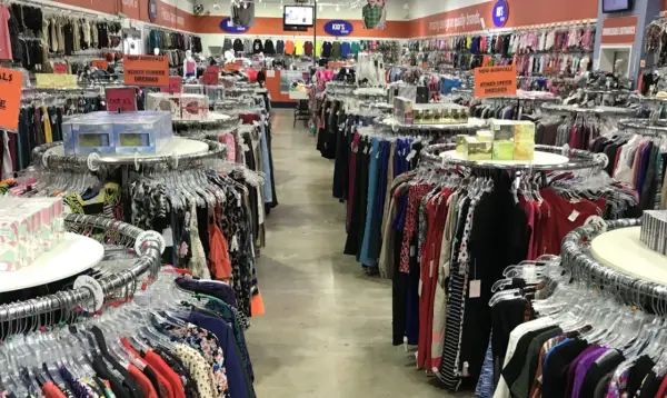 Pasillos llenos de ropa en una tienda, ideal para aprender como montar una tienda de ropa de segunda mano.