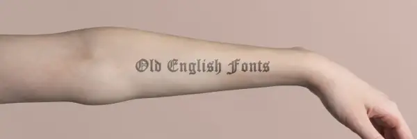 Ein Arm mit einem Tattoo-Schriftzug in Old English Fonts.