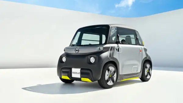 Najmniejszy Opel, Rocks-e, z żółtymi akcentami, prezentuje się nowocześnie na tle białej ściany i błękitnego nieba.