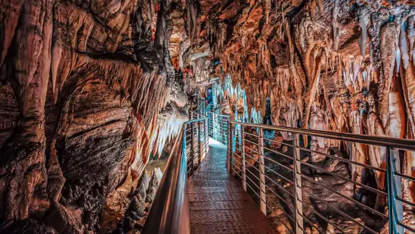 Sentiero illuminato tra stalattiti e stalagmiti nelle grotte in Toscana. Un viaggio sotterraneo tra formazioni rocciose millenarie.