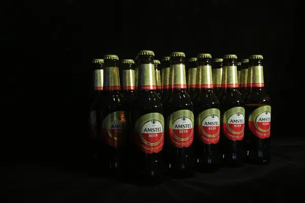 Rząd butelek piwa Amstel na czarnym tle. Czy piwo jest niezdrowe? To zależy od ilości.