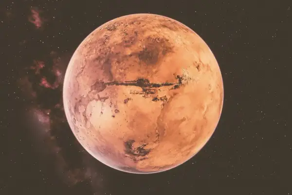 Czerwona planeta Mars, z widocznymi kraterami i kanionami, na tle gwiezdnego nieba. W tle widać mgławice, które mogą sugerować retrogradację Marsa.
