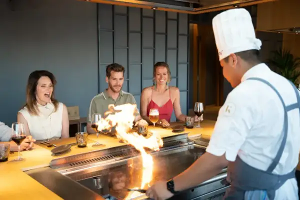 Chef prepara teppanyaki que es una experiencia culinaria interactiva. Los comensales disfrutan del espectáculo de fuego y la comida.