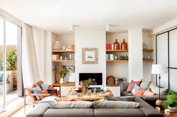 Ideas para un salón comedor acogedor con sofás grises, sillones de cuero, chimenea y estanterías llenas de libros y objetos decorativos.