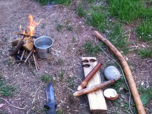 Un cuchillo, un cazo y leña para prender fuego. Preparativos para una noche al aire libre.