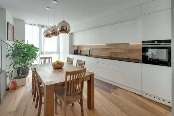 Tavolo in legno con sedie, ideale per chi vuole ristrutturare cucina. Illuminazione moderna e mobili bianchi.