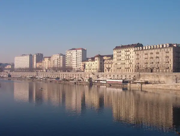 I **murazzi** di Torino si specchiano nel fiume, con palazzi storici e moderni che si affacciano sulla riva.
