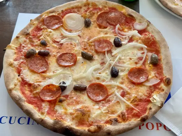 Eine köstliche Pizza mit Salami, Zwiebeln und Oliven, frisch aus i due forni.