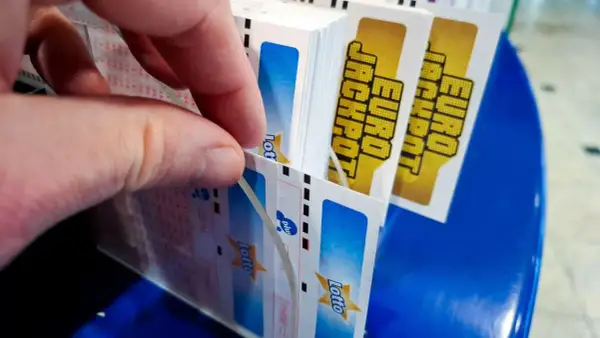 Dłoń wybiera kupony Eurojackpot. Dlaczego w Eurojackpot trudniej trafić siódemkę niż szóstkę w zwykłym Lotto? Więcej liczb do wyboru!