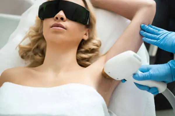Mujer con gafas protectoras recibe tratamiento de depilación láser SHR en axilas.