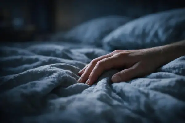 Mano su lenzuola stropicciate, un senso di ansia a mille nella notte.