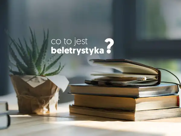 Co to jest beletrystyka? Stos książek i notes z ołówkiem, obok rośliny w doniczce.