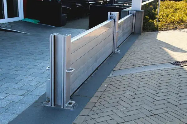 Moderne mobile Hochwasserschutzwand schützt das Haus vor Überschwemmungen. Sie ist aus Aluminium gefertigt und an den Pfosten befestigt.