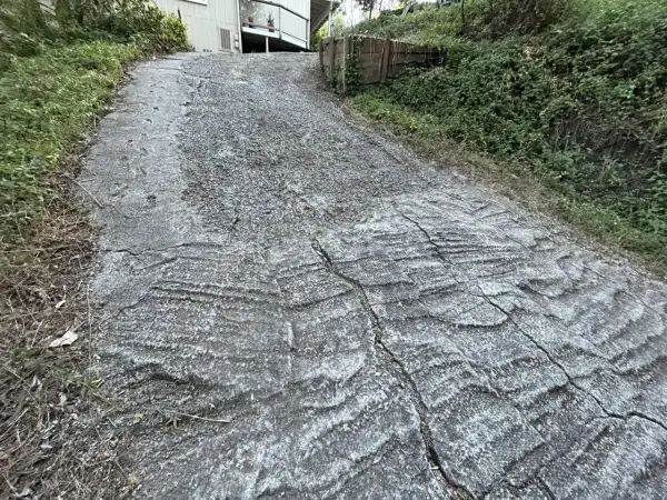 Stromy podjazd z popękanego betonu, z widocznymi śladami po koleinach. Zastanawiasz się, czym wyłożyć stromy podjazd?