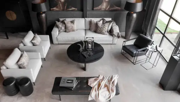 En modern lounge med soffa, fåtöljer och ett runt soffbord. En stilren och maskulin inredning med fokus på mörka toner och geometriska former.