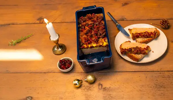 Une terrine maison aux airelles, servie sur toasts avec une bougie allumée. Une ambiance festive pour un délice.