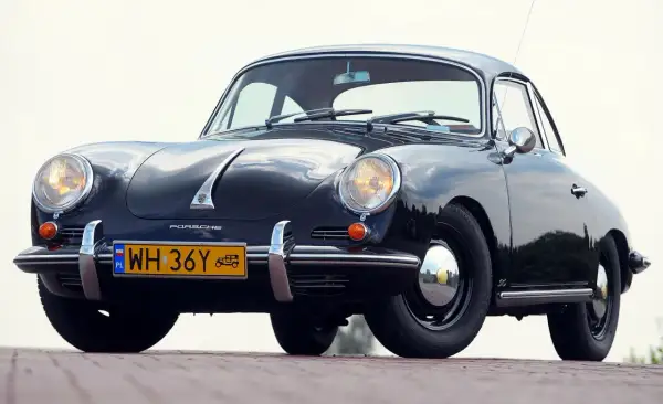 Czarne, zabytkowe auto Porsche z lat 50. XX wieku, z charakterystycznym przodem i żółtą tablicą rejestracyjną.