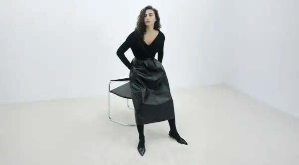 Elegancka czarna spódnica z ekoskóry, zestawiona z czarnym swetrem i butami. Stylowe czarna spódnica stylizacje.