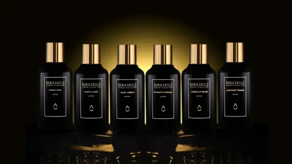 Sześć czarnych flakonów perfum Birkholz z złotymi nakrętkami. Jeden z nich to "Dark Amber", o głębokim, **dark amber** kolorze.