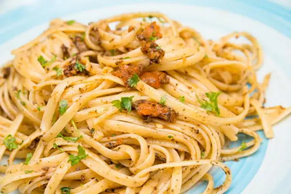 Linguine condite con un saporito sugo ai ricci di mare, guarnite con prezzemolo fresco.