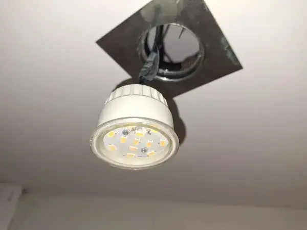 Oprawa natynkowa GU10 z widoczną żarówką LED, zamontowana na suficie.