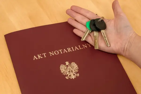Akt notarialny i klucze w dłoni. Komparycja dokumentów i symbolu własności.
