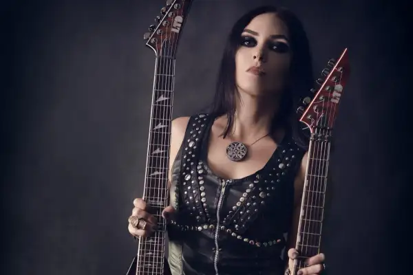Marta Gabriel, wokalistka i gitarzystka, z dwoma gitarami elektrycznymi w skórzanej kamizelce z ćwiekami.