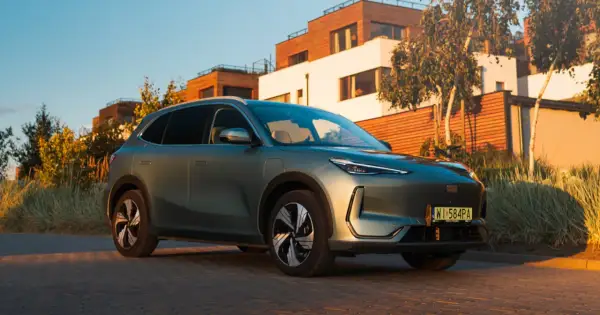 Nowy Geely EX5 w kolorze zielonym, zaparkowany przed nowoczesnymi domami.