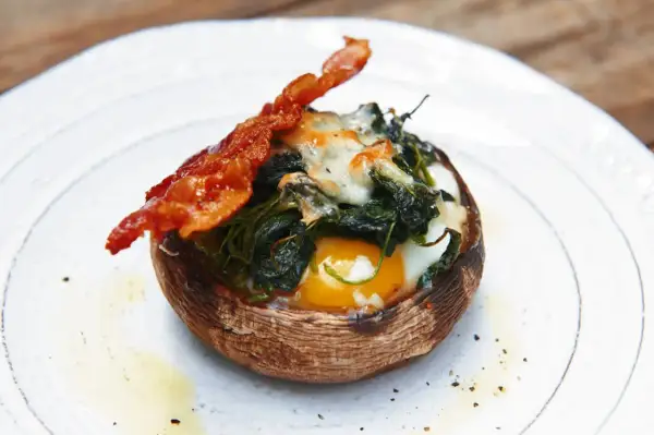 Gefüllter Portobello Pilz mit Ei, Spinat und Käse, garniert mit knusprigem Speck. Ein einfaches und leckeres Portobello Pilz Rezept.