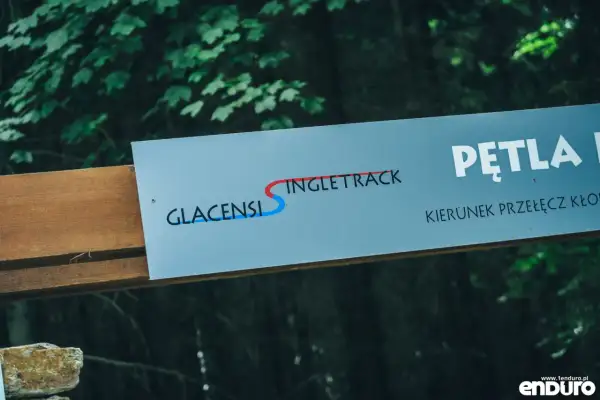 Tablica informacyjna z napisem "GLACENSIS SINGLETRACK" i strzałką wskazującą kierunek.