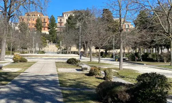 Passeggiata invernale nei giardini Diaz a Macerata, con alberi spogli e palazzi sullo sfondo.