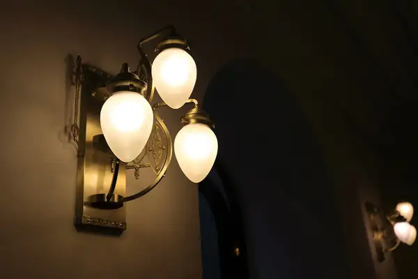 Elegancki kinkiet z trzema mlecznymi kloszami, rzucający ciepłe światło. Trudno ocenić ile lumenów na m2, ale tworzy przytulną atmosferę.