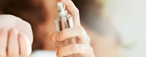 Eine Hand hält einen Glasflakon, bereit, einen selbstgemachten Erfrischungsspray aufzusprühen.