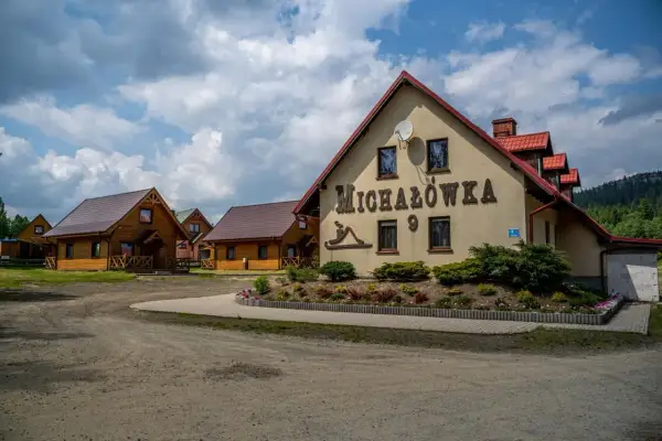 Ośrodek jazdy konnej Michałówka z drewnianymi domkami i głównym budynkiem z napisem "Michałówka".