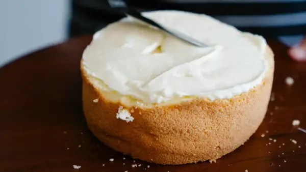 Bizcocho esponjoso cubierto con glaseado blanco cremoso, listo para decorar. Una deliciosa receta bizcocho.