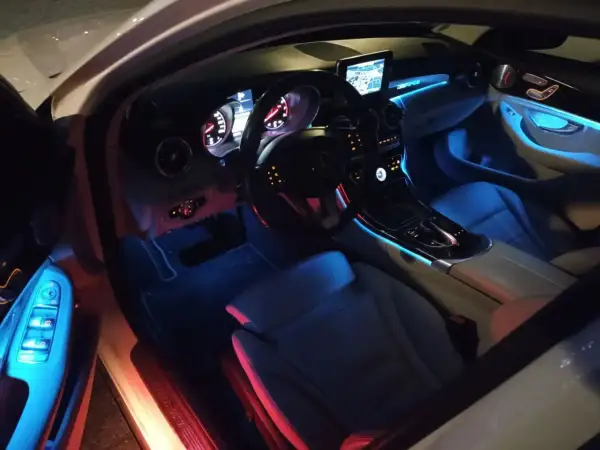Wnętrze Mercedesa C W205 z niebieskim i czerwonym oświetleniem ambientowym.