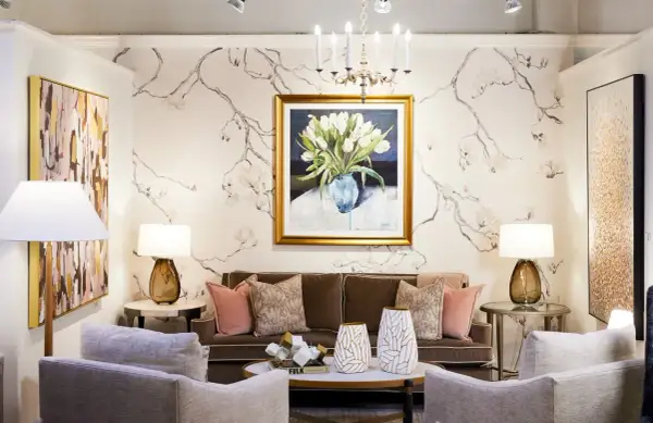 A living room with traditional interior design, featuring a floral wallpaper, a painting of tulips, a brown sofa, and plush armchairs.