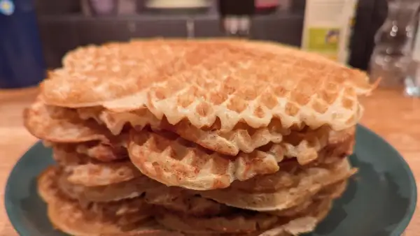 En hög med gyllene, glutenfria våfflor på en grön tallrik. Perfekt för en frukost eller fika.