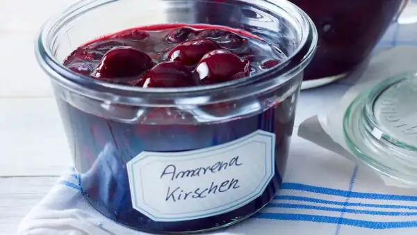 Ein Glas mit Amarena Kirschen, perfekt für ein Amarena Kirschen Rezept. Die dunklen Früchte schwimmen in Sirup.