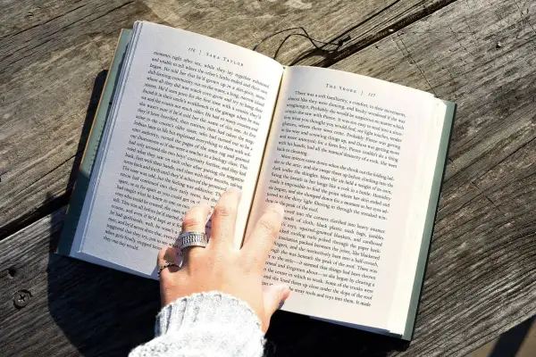 Dłoń z pierścionkami przewraca kartki książki. Czytanie to myślenie, a myślę więc jestem.