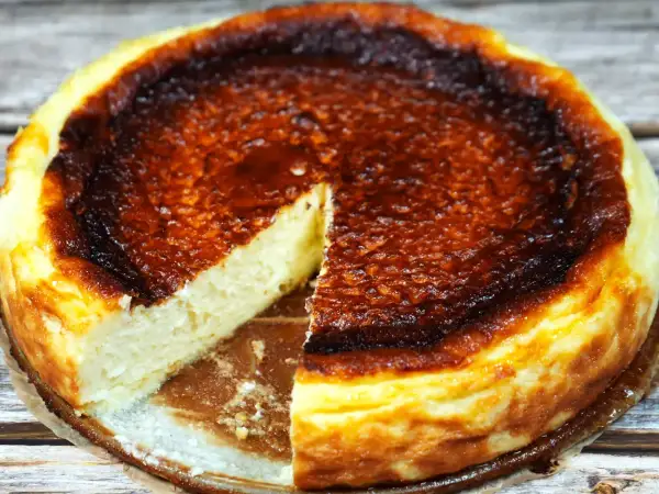 En krämig baskisk cheesecake med en härligt bränd yta, en bit är bortskuren.