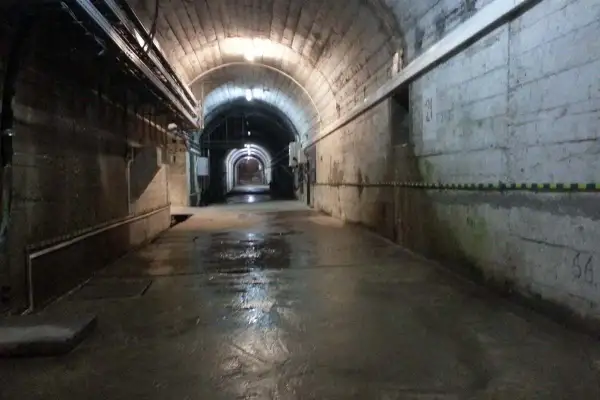 Wnętrze tunelu zapory Solina. Zwiedzanie cennik. Wilgotna posadzka, betonowe ściany, łukowe sklepienie z instalacjami.