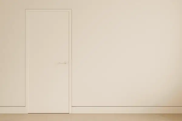 Puerta blanca minimalista con manija discreta y un rodapié enrasado que se funde con la pared, creando un espacio limpio y moderno.
