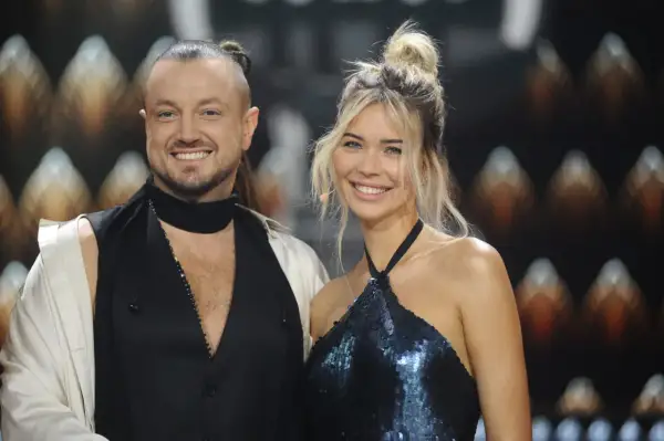 Sandra Kubicka i Baron uśmiechają się do obiektywu. Ona w błyszczącej sukience, on w nietypowej stylizacji.