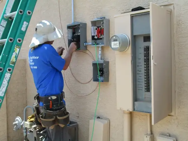 Elektryk pracuje przy skrzynce elektrycznej, podłączając przewody. To kluczowy etap instalacji, który zapewni odpowiednią moc przyłączeniową.